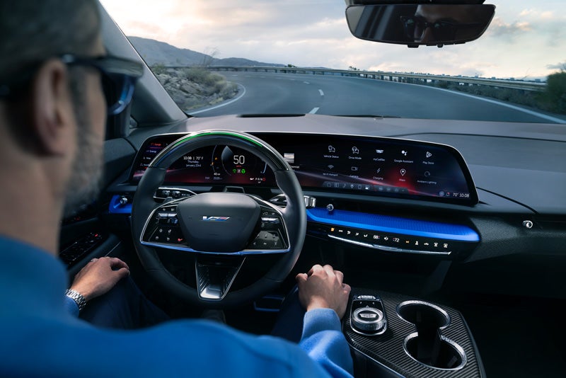 Front View of the 2026 OPTIQ-V Driving Through the Dusk Utilizing its Headlights | Charles Boyd Cadillac in HENDERSON NC