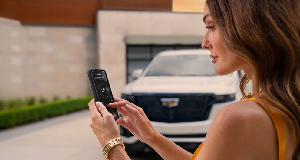 lady checking her mobile with a Cadillac vehicle background | Charles Boyd Cadillac in HENDERSON NC
